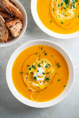 Pumpkin soup served in a bowl with croutons, parsley and olive oil.