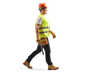 Full length profile shot of a construction worker with a helmet and tool belt walking