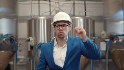 Portrait of serious businessman in hardhat walking in modern brewery workshop - Powered by Adobe