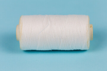 Textile industry, thread and needle, blue background, place for advertising or text