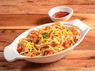Chicken Hakka Noodles a popular oriental dish made with chicken, noodles and vegetables, served over a rustic wooden background, selective focus