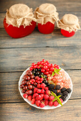 Assorted fresh summer berries and jam in jars. Raspberries, gooseberries, blackberries, currants, wild strawberries, strawberries.