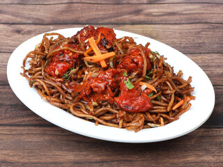 Chicken Noodles a popular indo chinese dish made with chicken, noodles and vegetables, served over a rustic wooden background, selective focus