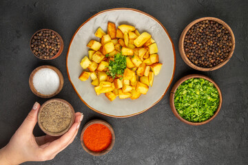 top view tasty fried potatoes inside plate with seasonings on dark background color oil kitchen dinner photo