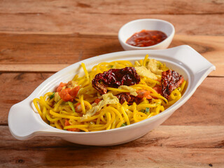 Chicken singapoori Noodles a popular indo chinese dish made with chicken, noodles and vegetables, served over a rustic wooden background, selective focus