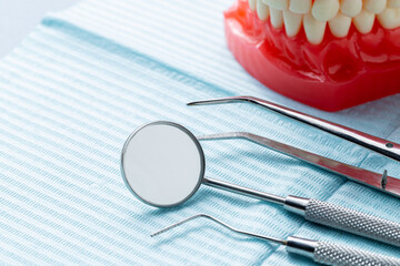 Different dental instruments and model of a mouth on a blue dental napkin inside of a dental office orthodontics teeth oral clinic - obrazy, fototapety, plakaty