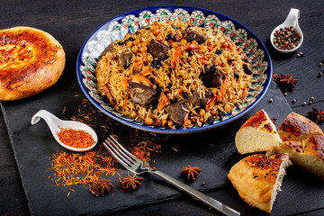 The concept of oriental cuisine. Assorted Uzbek food set, pilaf, samsa, lagman, manta, shurpa central asia food. Homemade Uzbek pilaf or plov from lamb served in cast iron cookware