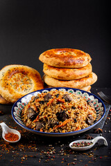 The concept of oriental cuisine. Assorted Uzbek food set, pilaf, samsa, lagman, manta, shurpa central asia food. Homemade Uzbek pilaf or plov from lamb served in cast iron cookware