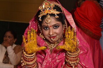 Obraz premium Bareilly, India 2019: Bride flaunting her palms with haldi on it. She is wearing traditional indian wedding dress and enjoying the ceremony 
