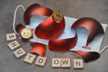 Zerbrochene rote Weihnachtskugeln auf Schutzmaske und Shutdown in Buchstaben