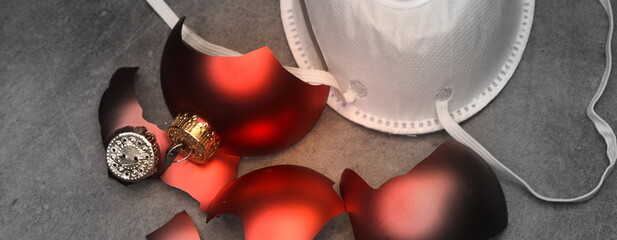 Zerbrochene rote Weihnachtskugeln und vor einer FFP2-Maske