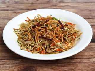 Veg Hakka Noodles a popular oriental dish made with noodles and vegetables, served over a rustic wooden background, selective focus