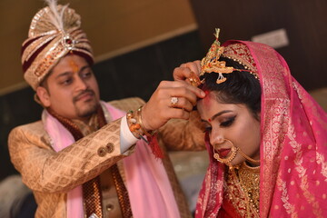 Groom applying sindoor also known as vermilion to bride during wedding ceremony as one of the rituals. This is a very auspicious activity of great importance during the ceremony 