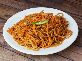 Veg Noodles a popular indo-chinese dish made with noodles and vegetables, served over a rustic wooden background, selective focus