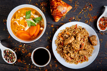 The concept of oriental cuisine. Assorted Uzbek food set, pilaf, samsa, lagman, manta, shurpa central asia food. Homemade Uzbek pilaf or plov from lamb served in cast iron cookware