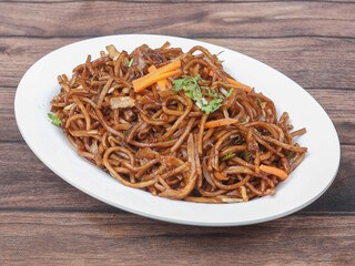 Veg Noodles a popular indo-chinese dish made with noodles and vegetables, served over a rustic wooden background, selective focus