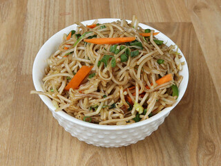 Veg Noodles a popular indo-chinese dish made with noodles and vegetables, served over a rustic wooden background, selective focus