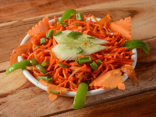 Schezwan Veg Noodles a popular indo-chinese dish made with noodles, vegetables and schezwan sauce, served over a rustic wooden background, selective focus