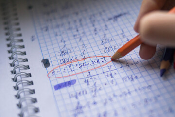 Office. Study. Man's hand writes with a colored pencil on paper. Formula sheet. Mathematics. Notebook on rings.
