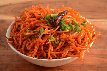 Schezwan Veg Noodles a popular indo-chinese dish made with noodles, vegetables and schezwan sauce, served over a rustic wooden background, selective focus