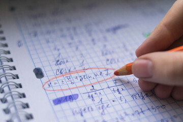 Office. Study. Man's hand writes with a colored pencil on paper. Formula sheet. Mathematics. Notebook on rings.