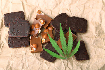 Pieces of chocolate with cannabis CBD nuts with dry green hemp leaf. Hemp biscuits covered with chocolate glaze. Marijuana sweet food concept