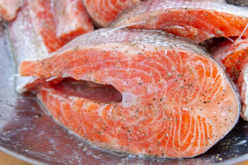 Fresh trout steaks are marinated in a metal bowl before cooking