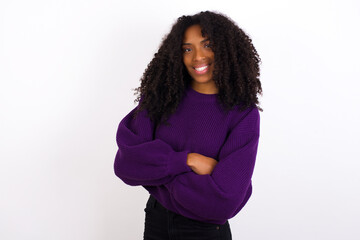 Young beautiful African American woman wearing knitted sweater against white wall,   happy face smiling with crossed arms looking at the camera. Positive person.