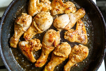 Marinated chicken drumsticks and wings in a pan.