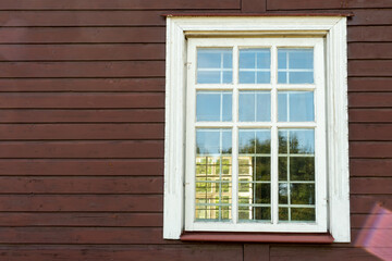 White wooden antique window on a wooden building. Old well-kept wooden house. Old Church and Windows with a cross.