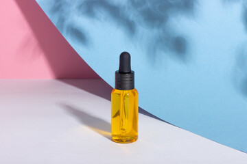 Serum bottle with dropper with shadows on the background. Skincare beauty spa product and pipette