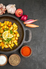 top view tasty fried potatoes inside pan with onions and garlics around on dark background color meal food calorie