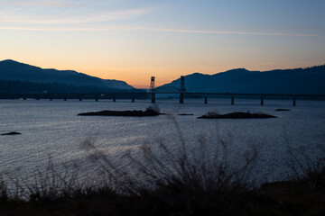 A beautiful bridge over a wide river against the backdrop of mountains at sunset. Autumn landscape at sunset with picturesque mountains, lake and bridge on the horizon. Hood river bridge, Bingen, WA