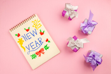 top view little presents with notepad on pink background photo color new year christmas gift family