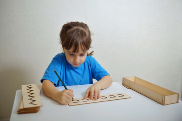 Insert templates for preparing the preschooler's hands for writing. Early development concept. The girl is learning to write.