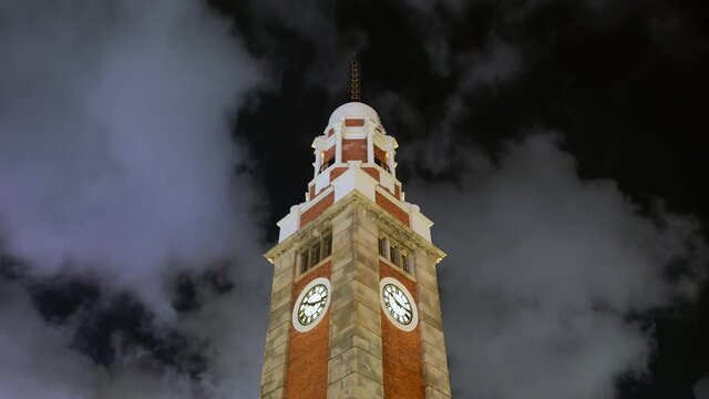 Night time lapse view of dramatic skies over historical landmark Tsim Sha Tsui Clock Tower, completed in 1915, near Victoria Harbour in Kowloon, Hong Kong, China. 
