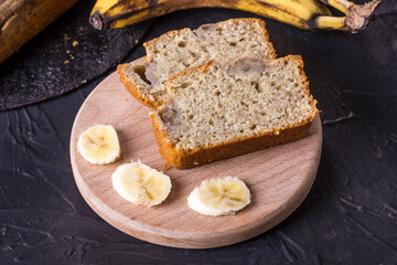Pieces of traditional American banana bread on a wooden board on a black concrete background