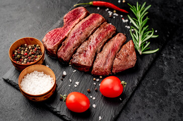 Different degrees of roasting beef steak in heart shape with spices on a stone background