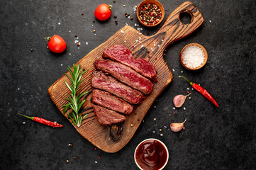 Different degrees of roasting beef steak in heart shape with spices on a stone background