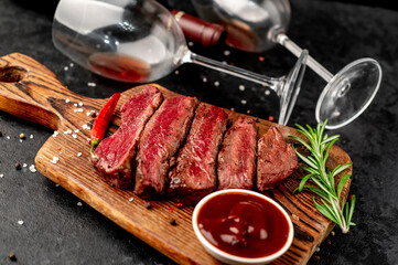 Dinner for two .Various degrees of roasted beef steak in the shape of a heart with spices and bottles of red wine with glasses on a stone background. valentines day celebration concept