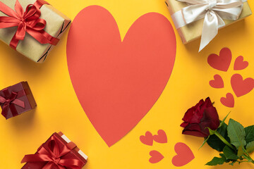 red rose on a yellow background, several beautiful wrapped boxes. Large cardboard heart.Place for your text. Background for lovers