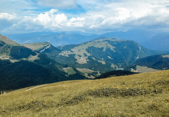Beautiful view of the peaks of Monte Baldo. Stunning cloudy and panoramic view. Green Pastures in Italian Alps