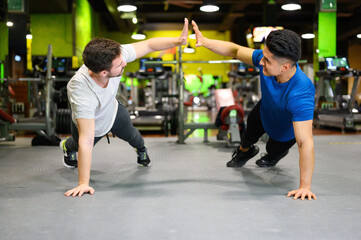 Two young men doing high planks in gym. High quality photo