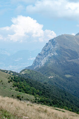 Beautiful view of the peaks of Monte Baldo. Stunning cloudy and panoramic view. Green Pastures in Italian Alps
