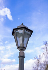 Fototapeta na wymiar Street lamp with a classic lamppost against a cloudy sky background. Vintage style outdoor lamppost