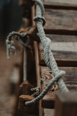 Close up of rope twirled and knotted on a wooden construction in the park