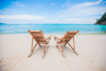 Fototapeta na wymiar White lounge chairs on a beautiful tropical beach