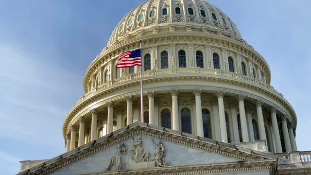 A close up of the United States Capitol dome and the waving US national flag