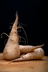 A trio of parsnips, set upon a wooden board, showing them to be a root vegetable.