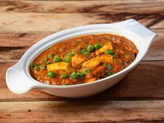 Matar Paneer masala recipe made using cottage cheese, green peas, served over a rustic wooden background, selective focus